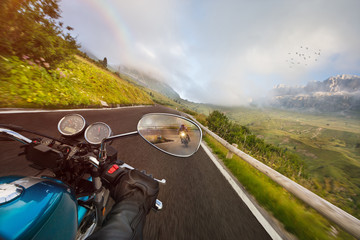 Naklejka premium Motorcycle driver riding in Alpine highway, handlebars view, Dolomites, central Europe.