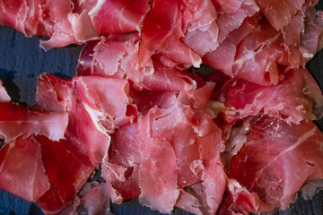 Slices of italian speck on a black background