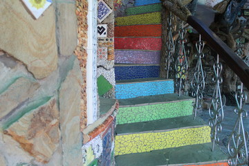 photo of a fabulous staircase.her steps are iridescent and colorful .a small tile of red, green, blue, yellow.the railing is openwork, made of metal.