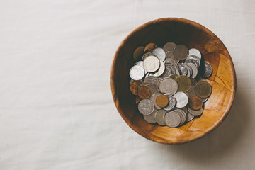 Coins in a wooden bowl, donate and give concept.