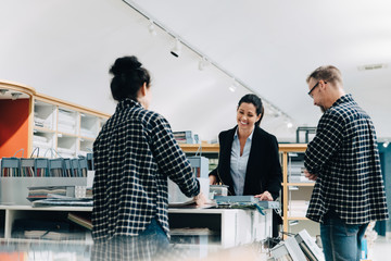 Sales employees assisting female customer in store