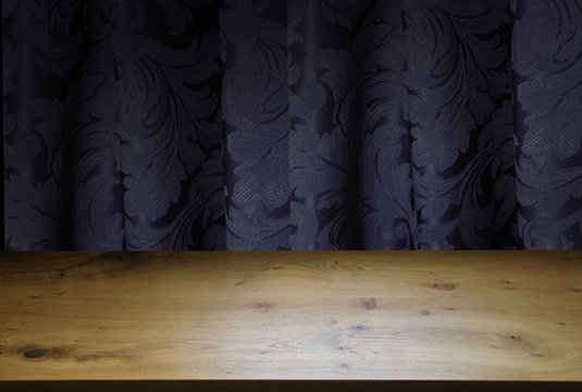 Wooden table, black background and dark blue drapery. Free space for your design