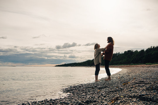 Full length of couple standing on sea shore at beach against sky