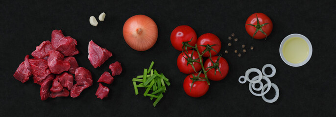 GMO free food: tomatoes, beef, onion, garlic, black pepper and bowl with oil on black stone cutting...