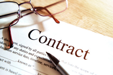 Contract sheet with glasses and a pen on a wooden background