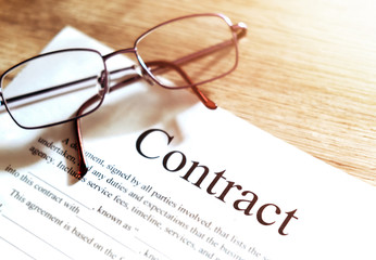 Contract sheet with glasses on a wooden background
