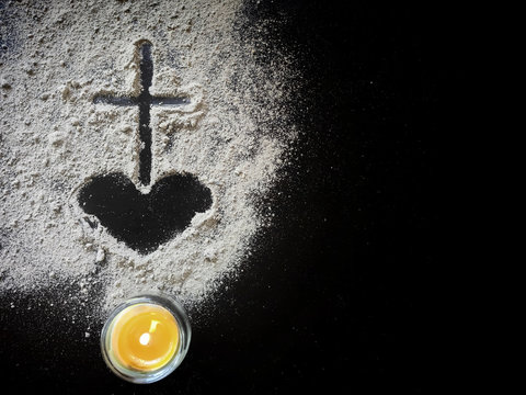 Lent Season,Holy Week and Good Friday concepts - Image of ash in shape of heart and cross with candle light on dark background