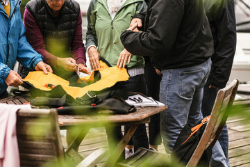 Midsection of senior men and women with life jacket at table during boat master course on pier