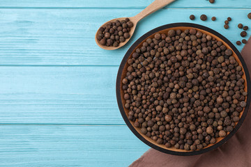 Peppercorns on light blue wooden table, flat lay. Space for text