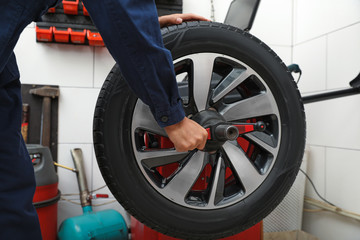 Man working with wheel balancing machine at tire service, closeup