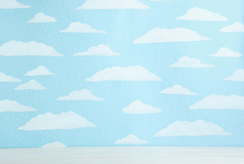 White wooden table near wall with painted blue sky. Idea for baby room interior
