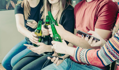 Young friends drink alcohol and use smartphones - Millennials party after skiing - Friends raise a toast for a good day and send messages on social networks.