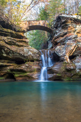 Scenic waterfall under bridge and natural rock formations