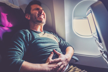 Man passenger in airplane suffer from airsick with stress headache and stomach ache in a flight time. Close up photo realistic