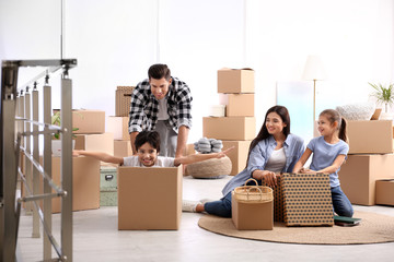 Happy family having fun while unpacking moving boxes at their new home