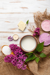 Spa and bath cosmetics with lilac flowers. Bath salt, soap, cream, oil, milk, serum and towel rolls on wooden rustic background. Organic natural cosmetic. Fresh care of body. Eco lifestyle
