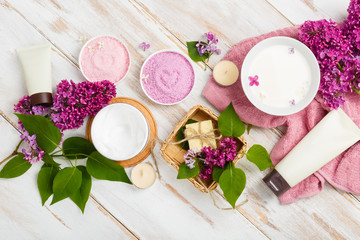 Spa and bath cosmetics with lilac flowers. Bath salt, soap, cream, oil, milk, serum and towel rolls on wooden rustic background. Organic natural cosmetic. Fresh care of body. Eco lifestyle