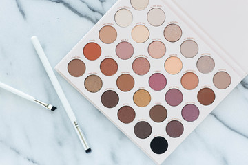 Neutral eyeshadow makeup palette on marble background