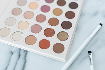 Neutral eyeshadow makeup palette on marble background