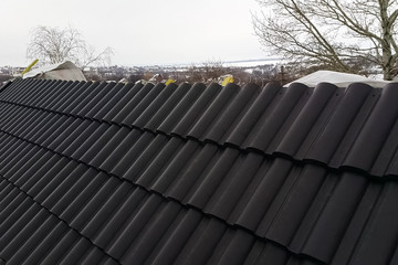 Installation of the roof of the house from ceramic black tiles.
