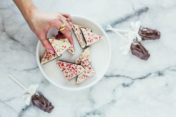 Peppermint white chocolate bark and chocolate suckers on marble background