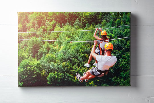 Canvas Print. Photo Hanging On A White Wooden Wall, Front View. Color Photography With Image Of People On Zip Line. Interior Decor