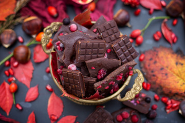 Gold cup of raw chocolate on a dark table with red autumn leaves