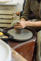 The girl sits at the Potter's wheel and creates a pot of ceramics. A Potter makes pottery out of clay behind a mechanical circle