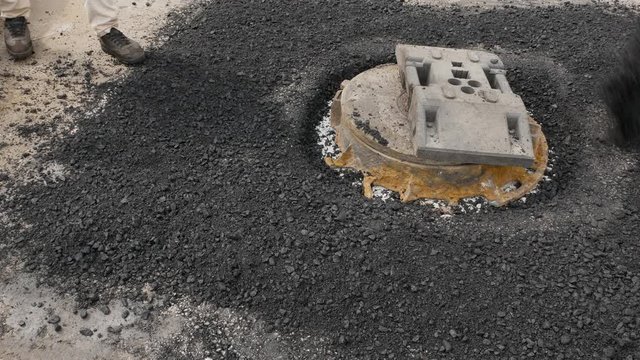 Worker spreads on hot asphalt for car road reparig
