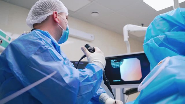 Doctor using laparoscopic equipment. Back view of doctor looks at monitors while preforming operation in hospital