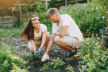 Woman works in a garden. Family near home with vegetables