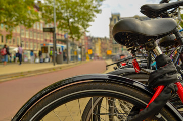 Amsterdam, Holland, August 2019.A particular point of view: from the blurred frame and saddle of a parked bike we see the cyclists passing on the cycle path