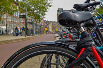 Amsterdam, Holland, August 2019.A particular point of view: from the blurred frame and saddle of a parked bike we see the cyclists passing on the cycle path