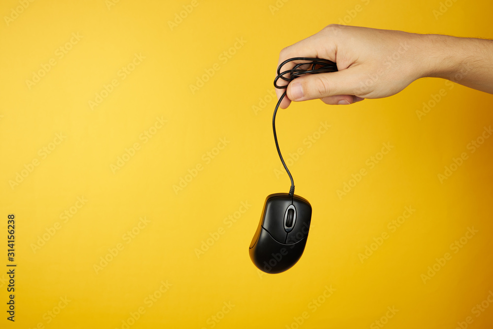 Aufkleber the black computer mouse at hand on a yellow background with copy space. hardware maintenance servic