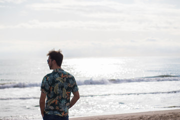 Model man walking at the beach and looking at the ocean.