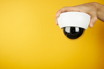 The wait cctv surveillance camera at palm on a yellow background with copy space. security and...