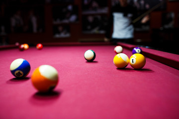 Boy plays billiard or pool in club. Young Kid learns to play snooker. Boy with billiard cue strikes the ball on table. Active Leisure, sport, hobby concept