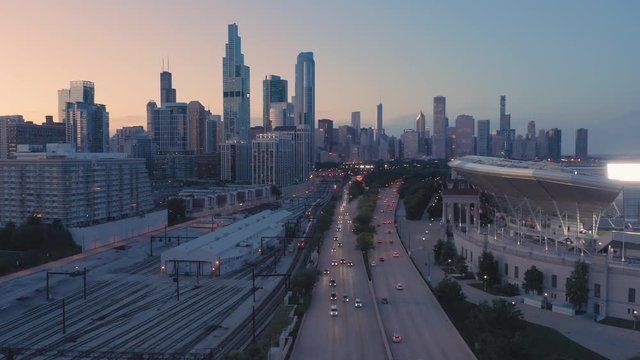 Aerial: Rush hour traffic, train tracks and Chicago skyline at night. USA