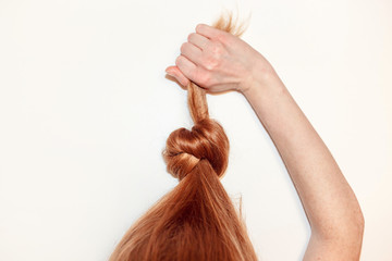 Red-haired girl pulls herself up in a knotted hair