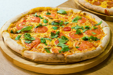 national italian food. traditional pizza with tomatoes and different types of cheese on a wooden board in a restaurant.