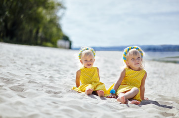 Adorable childs in dress posing outdoors. Little baby girls relaxing by the sea. Girls having fun together. Concept of summer,childhood and leisure