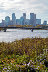 Vertical photo of Minneapolis skyline with the Mississippi River in the foreground
