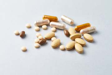 Multicolor vitamins and supplements on bright paper background. Concept for a healthy dietary supplementation. Close up. 
