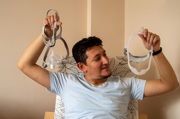 Young man is trying to choose which mask he will use for his sleep apnea disease, nasal CPAP mask...