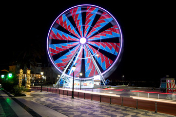 A night image of a 32 meter high Ferris wheel with varying illumination.