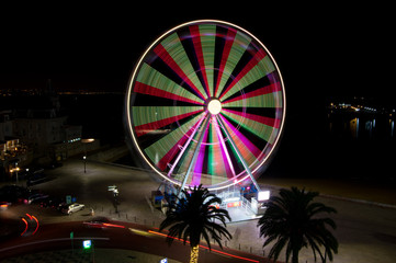 A night image of a 32 meter high Ferris wheel with varying illumination.