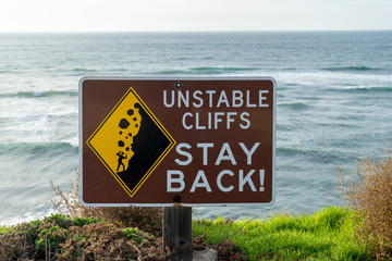 Unstable Cliff - Stay Back sign with ocean background