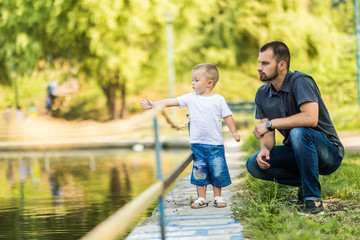 Father and son having fun near lake in summer park. Family concept.