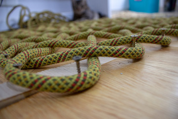 The process of making a rope rug, using an old climbing rope. Using a wooden board with screws to help.