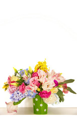 Bouquet of flowers on a shelf by the wall. Flowering branches in a bucket with a pea pattern